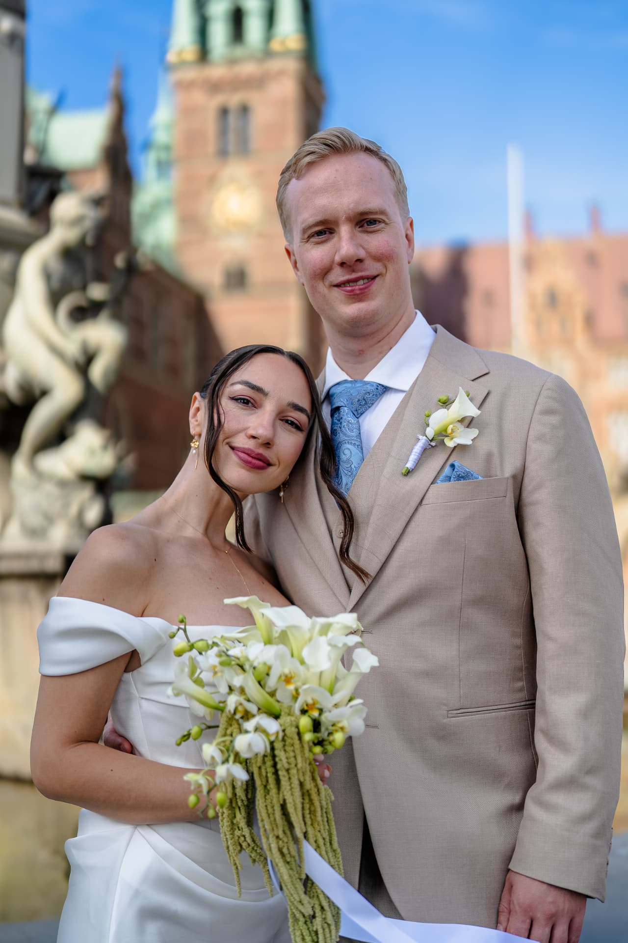 Wedding photographer Copenhagen — smiling bride and groom cheek to cheek with bridal bouquet at Frederiksborg Slot castle
