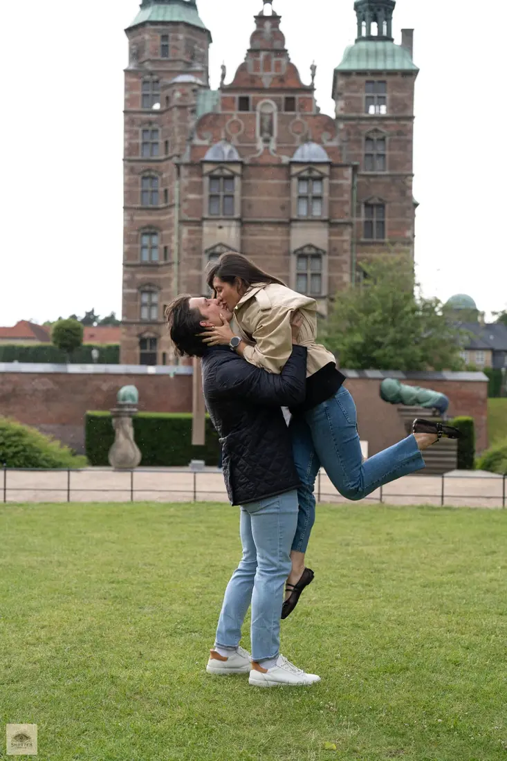 Groom-to-be lifting his fiancée in front of Rosenborg Castle, Copenhagen proposal and engagement photoshoot